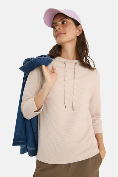 Beige T-shirt met lange mouwen van CECIL, getextureerd met trekkoord, gedragen met een pet en een spijkerjasje.