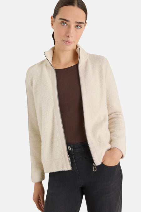 Ecru vest van CECIL, gedragen met een bruin T-shirt en een casual zwarte jeans en witte sneakers.