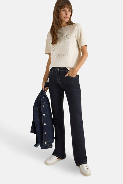 T-shirt écru à manches courtes de Cecil, avec un imprimé graphique, porté avec un jean et des baskets blanches.
