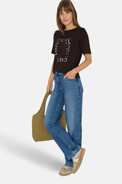 Bruin T-shirt met korte mouwen van Cecil, met een tekstprint, gedragen met een spijkerbroek en een olijfgroene tote bag.