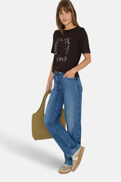 Bruin T-shirt met korte mouwen van Cecil, met een tekstprint, gedragen met een spijkerbroek en een olijfgroene tote bag.