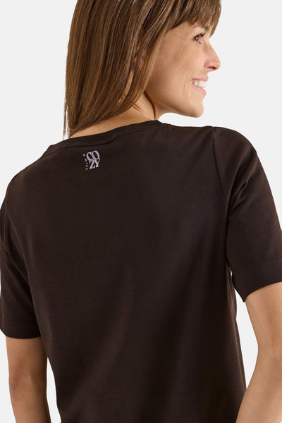 Bruin T-shirt met korte mouwen van CECIL, met een klein logo op de rug gedrukt, gedragen door een lachende vrouw.