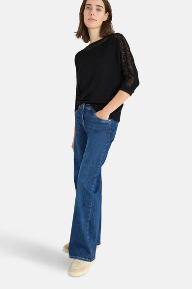 T-shirt à manches longues noir de CECIL, avec détails en dentelle aux manches, porté avec un jean bleu.
