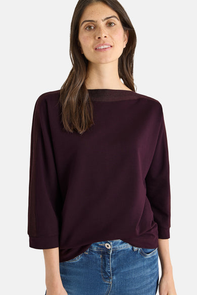 Bordeaux T-shirt met lange mouwen van CECIL, gedragen met een wijde blauwe jeans en sneakers.