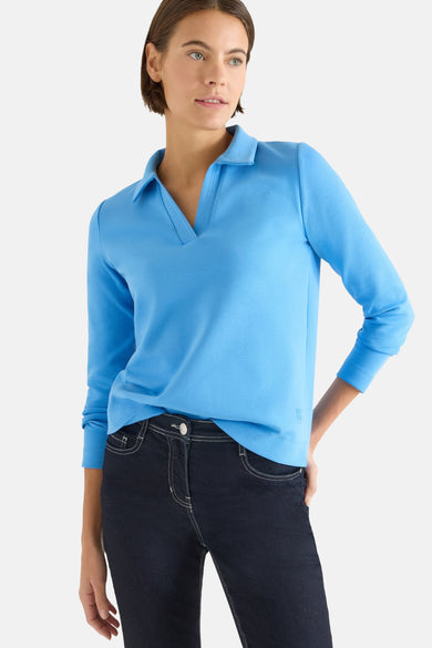 T-shirt bleu à manches longues de CECIL, porté avec un jean foncé à coutures blanches.
