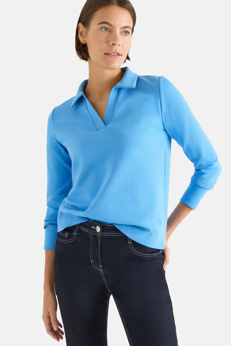 T-shirt bleu à manches longues de CECIL, porté avec un jean foncé à coutures blanches.