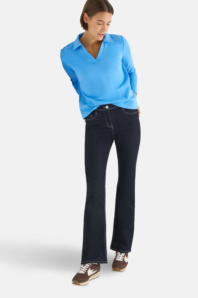 T-shirt bleu de CECIL, col polo et manches longues, porté avec un jean et des baskets marron.