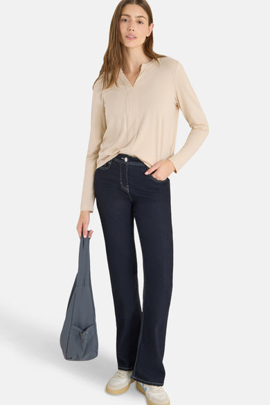 Chemisier beige à manches longues de CECIL, porté avec un jean bleu foncé et un sac gris.
