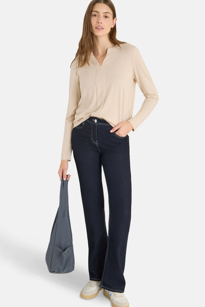 Chemisier beige à manches longues de CECIL, porté avec un jean bleu foncé et un sac gris.
