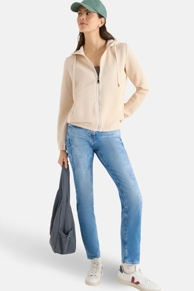 Gilet beige de CECIL avec une texture gaufrée, porté avec un jean bleu et un sac gris.
