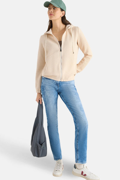 Gilet beige de CECIL avec une texture gaufrée, porté avec un jean bleu et un sac gris.
