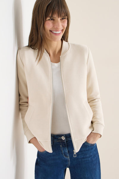Beige vest van CECIL, gedragen met een wit T-shirt en een blauwe jeans.