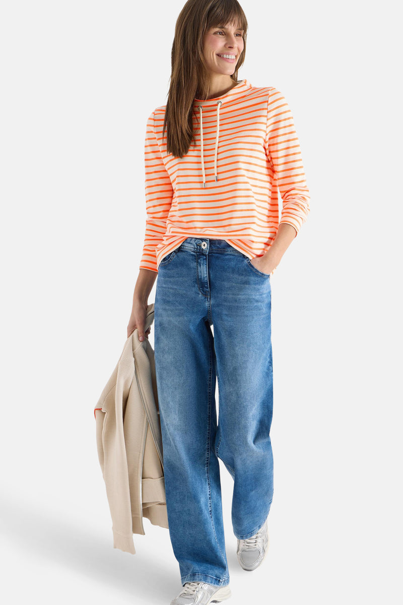 Multikleurig T-shirt met lange mouwen van CECIL, oranje en witte strepen, gedragen met een wijde blauwe jeans.