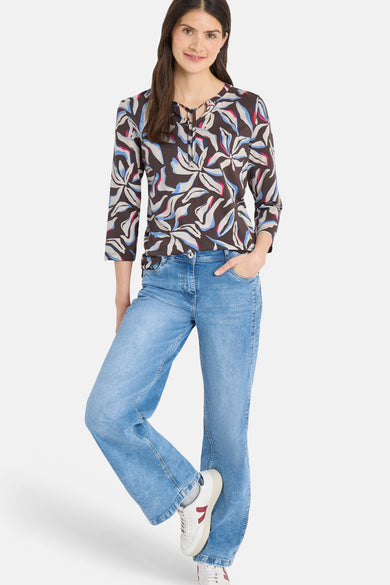 T-shirt à manches 3/4 multicolore de CECIL, avec motif floral et liens décoratifs au col, porté avec un jean bleu et des baskets blanches.
