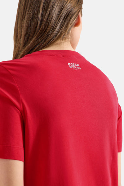 Red short-sleeve t-shirt with white "ocean waves club" text on back, worn by model, back view