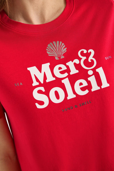 Red short-sleeve t-shirt with white "Mer & Soleil" graphic and silver shell, sea, sun, sand & shell text, close-up front view