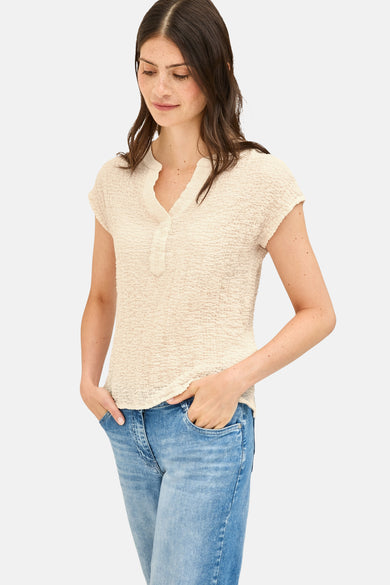 Beige blouse met korte mouwen van CECIL, met V-hals en wafelstructuur, gedragen met een spijkerbroek.