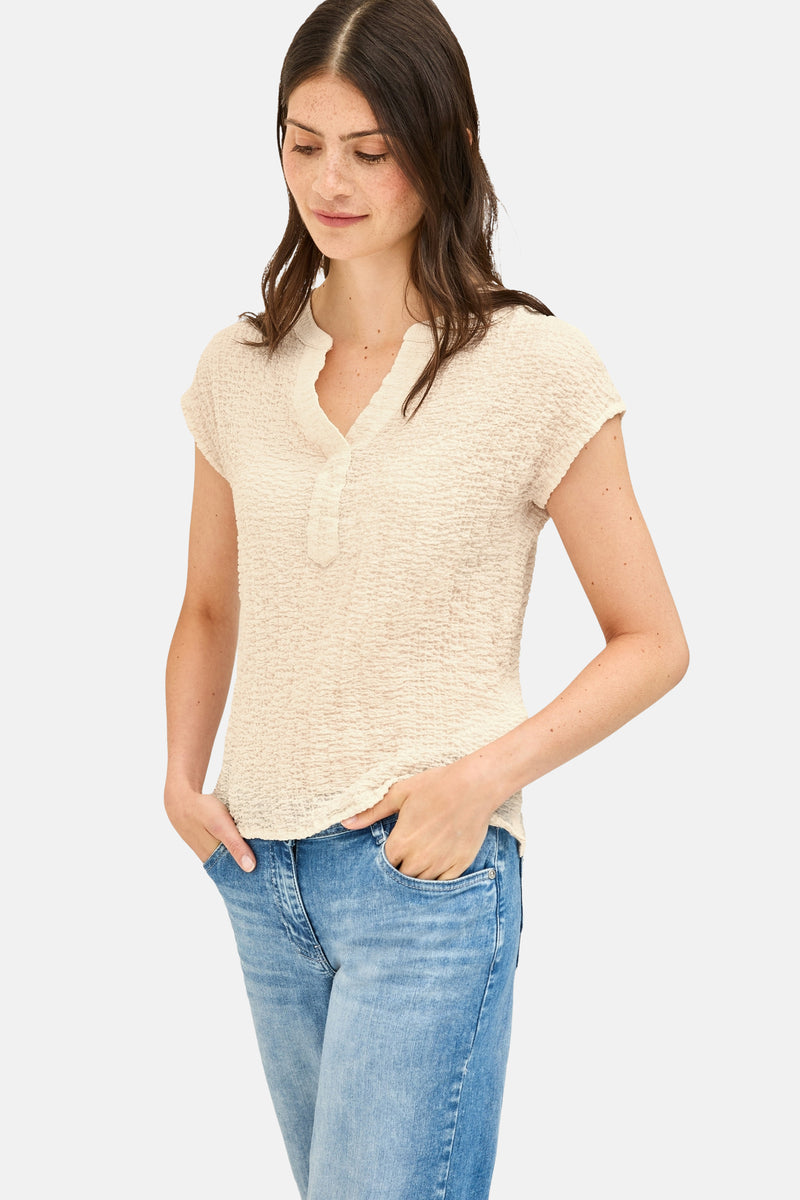 Beige blouse met korte mouwen van CECIL, met V-hals en wafelstructuur, gedragen met een spijkerbroek.