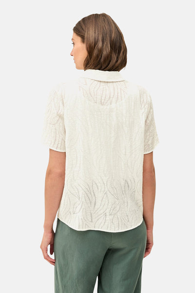 Blouse blanche à manches courtes de CECIL, avec un motif texturé délicat, portée avec un pantalon vert olive.
