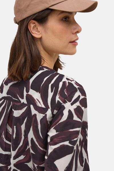 Bordeaux blouse met lange mouwen van CECIL, met een bruin en wit abstract patroon, gedragen met een beige pet.