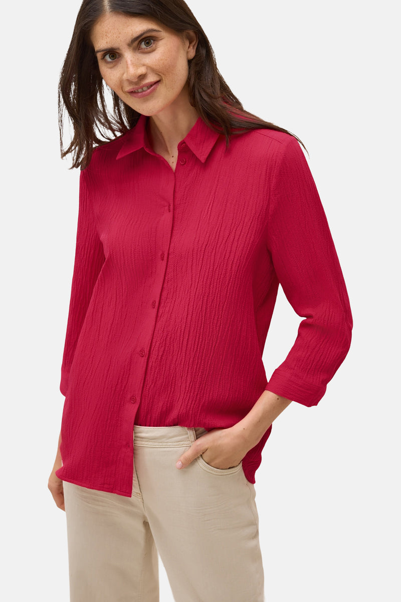 Rood overhemd met lange mouwen van CECIL, getextureerd, gedragen met een beige broek en de hand in de zak.