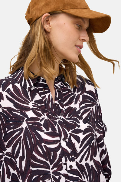 Bordeaux blouse met korte mouwen van CECIL, met donker bloemenpatroon op een witte achtergrond, gedragen met een bruine pet.