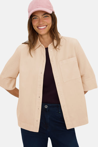 Beige overhemd met korte mouwen van CECIL, van ribfluweel, gedragen met een bordeauxrood T-shirt en een donkerblauwe broek.