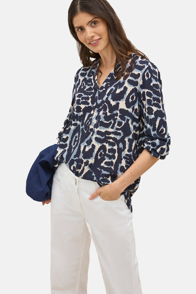 Blouse met lange mouwen in het blauw van CECIL, met diverse patronen, gedragen met een witte broek en een spijkerjasje.