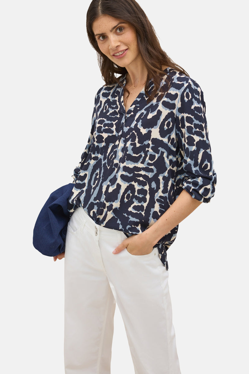 Blouse met lange mouwen in het blauw van CECIL, met diverse patronen, gedragen met een witte broek en een spijkerjasje.