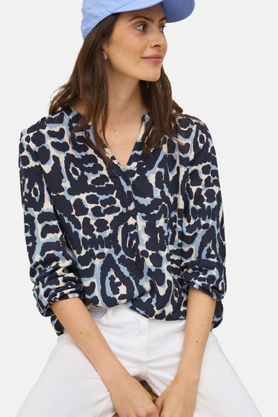 Blauwe blouse met lange mouwen van CECIL, met een abstract patroon en gedragen met een witte broek.