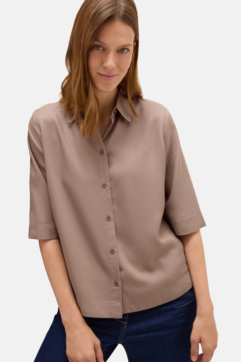 Taupe blouse met korte mouwen van CECIL, met een centrale knoopsluiting en gedragen met een donkerblauwe jeans.