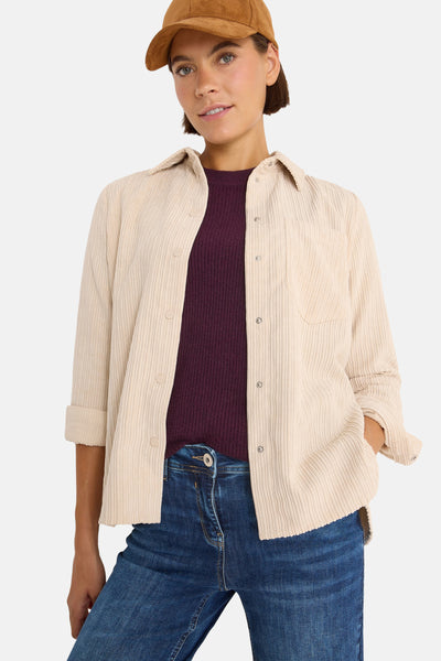 Beige blouse (lange mouwen) van CECIL, van ribfluweel, gedragen met een bordeauxrode T-shirt en een blauwe jeans.