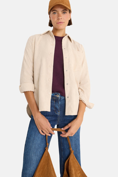 Beige blouse met lange mouwen van CECIL, van ribfluweel, gedragen open over een pruimkleurige trui, met een blauwe jeans.