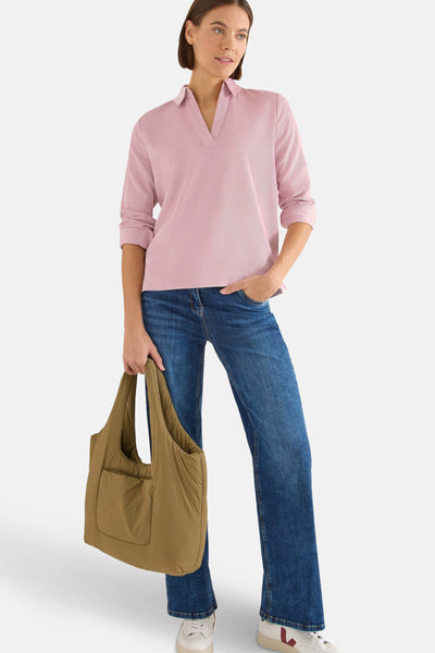 Chemisier à manches longues rose de CECIL, texture plissée, porté avec un jean bleu et un sac.
