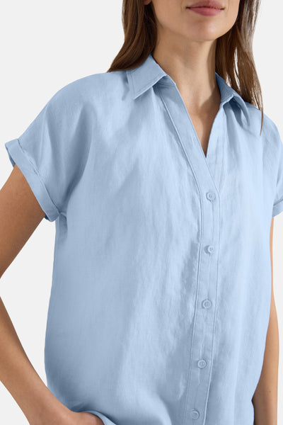 Light blue short-sleeve blouse with button-down front and rolled cuffs, cropped view on model
