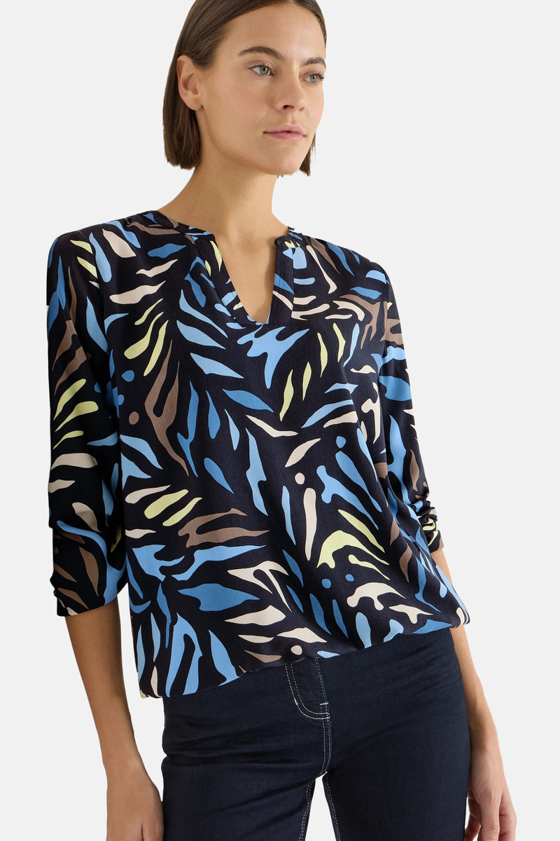 Multikleurige blouse met lange mouwen van CECIL, met een abstract patroon in blauw, bruin en geel op een zwarte achtergrond.