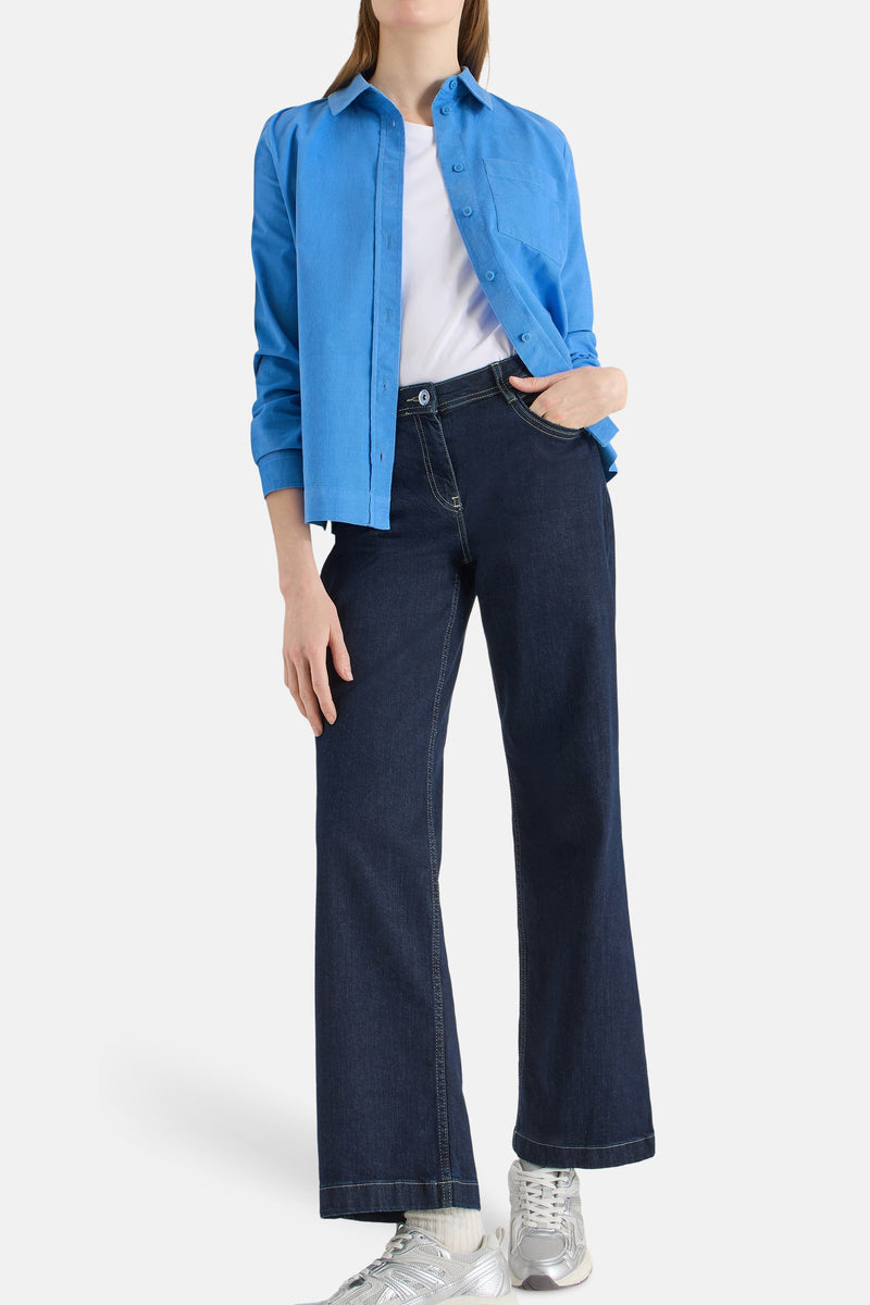 Blauwe blouse met lange mouwen van CECIL, gedragen open over een wit T-shirt met een donkere jeans.