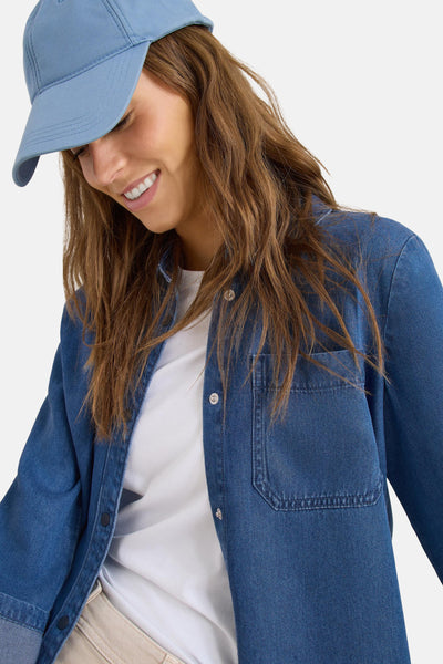 Middelblauwe spijkerblouse van CECIL, gedragen over een wit T-shirt met een blauwe pet.