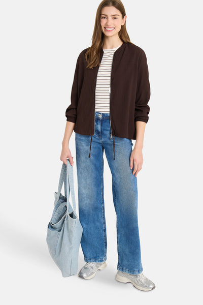 Gilet marron de CECIL, porté sur un t-shirt rayé, avec un jean bleu et un sac en denim.