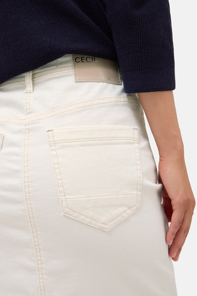 Jupe courte en denim off white de CECIL, avec une poche arrière et un pull bleu marine visible.