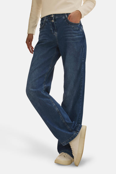 Jean large en denim bleu moyen de CECIL, porté avec un pull crème et des baskets blanches.