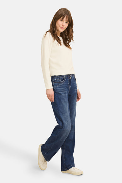 Jean large en denim bleu moyen de CECIL, porté avec un pull crème et des chaussures en toile assorties.