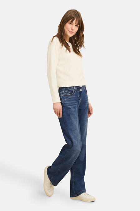 Jean large en denim bleu moyen de CECIL, porté avec un pull crème et des chaussures en toile assorties.
