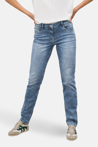 Jean slim en denim bleu clair de CECIL, porté avec un t-shirt blanc et des baskets en cuir.
