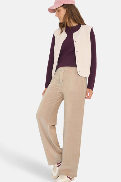 Beige ribfluwelen broek van CECIL, losse pasvorm, gedragen met een paarse trui en een imitatiebontvest.