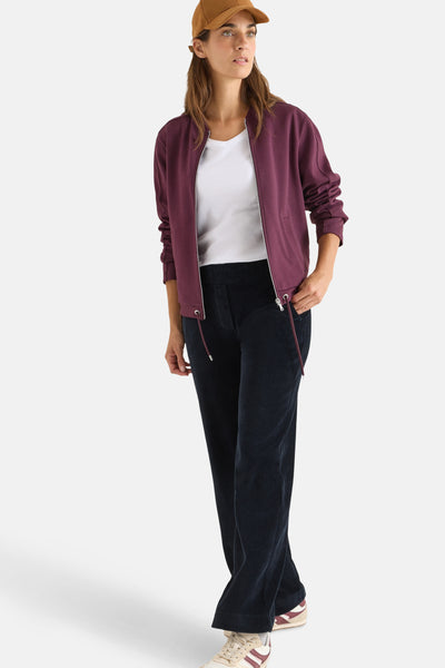 Cecil blauwe corduroy broek, gedragen met een wit T-shirt en een bordeauxrode jas.