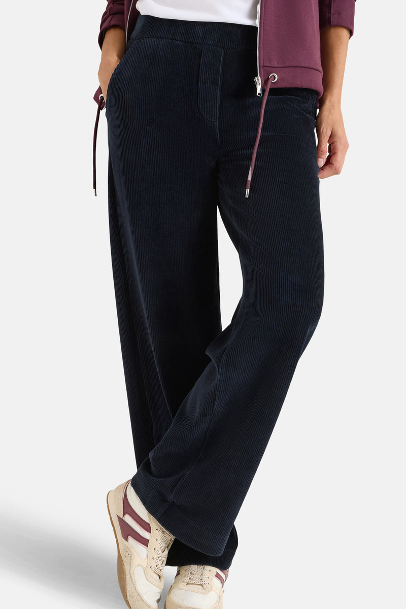 Blauwe corduroy broek van CECIL, losse pasvorm en wijde pijpen, gedragen met sneakers en een witte top.