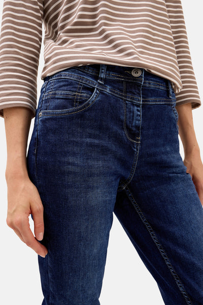 Jean slim en denim bleu moyen de CECIL, avec coutures apparentes et porté avec un haut rayé.
