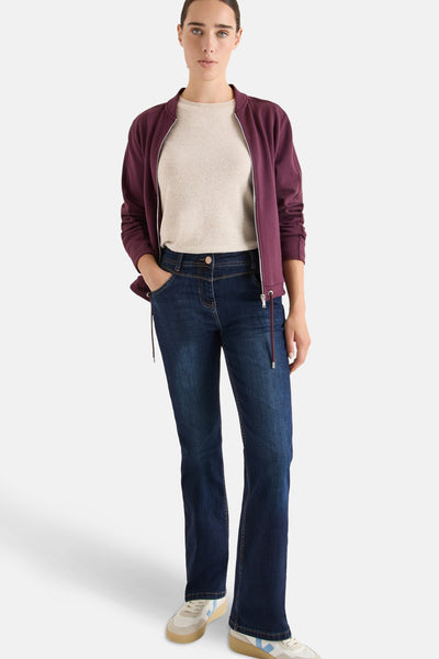 Bootcut jeans in donkerblauw denim van CECIL, gedragen met een beige T-shirt en een bordeauxrode jas.