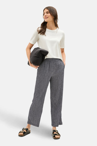 Pantalon bleu texturé de CECIL, porté avec un t-shirt blanc et des sandales à boucles.